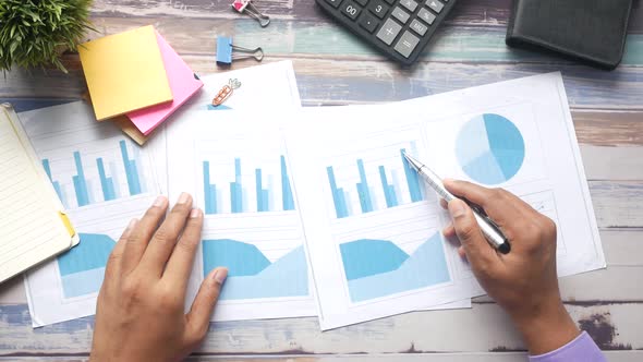 Man Hand with Pen Analyzing Bar Chart on Paper