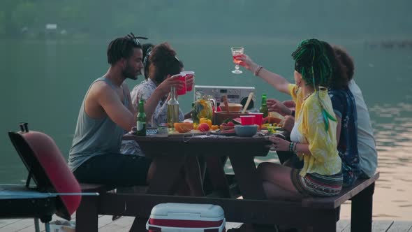 Young People Toasting and Drinking at Lake Party