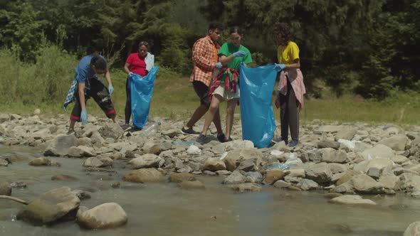 Group of Ecologically Aware Diverse Multiethnic Volunteers Cleaning Up Riverbank From Trash