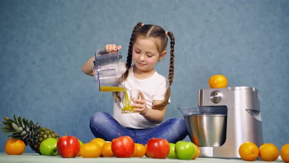 Girl drinking fresh juice. Little girl pours orange juice into the glass