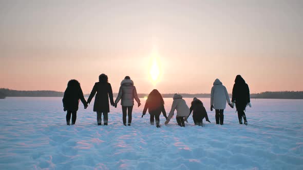 A Group of Girls Friends are Throwing Snow Up at Sunset