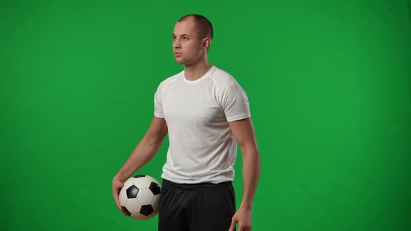 Confident Positive Caucasian Young Footballer with Soccer Ball Standing at Chromakey Background