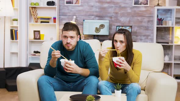 Couple Sitting on Couch Eating Noodles with Chopstick