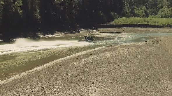 A drone chases a speedboat through a narrow winding section of river.