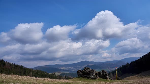 Turistická značka pri skale, oblaky v pohybe nad jarnou horskou krajinou