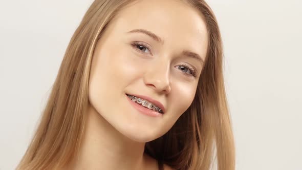 Young Girl with Braces on Teeth Looking at Camera and Smiling. White