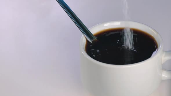 Slow Motion Shot of White Sugar Being Poured Into a Black Coffee