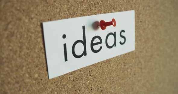Sticky note: IDEAS - Pinned to cork wall - and red