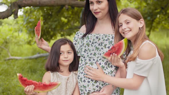 Pregnant Caucasian Woman and Her Two Pretty Daughters Standing Together in Hugs