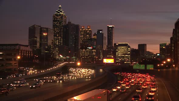 Static, wide, nighttime shot of the lit up Atlanta Skyline with traffic below.