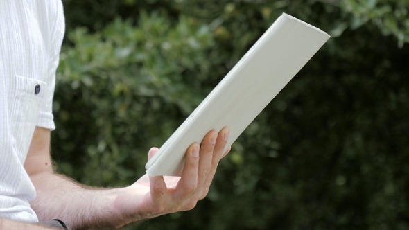 Man hands holding digital tablet in nature.