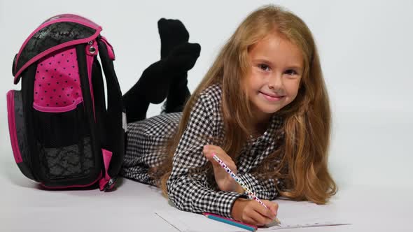 Smiling teen with school bag lying on the floor