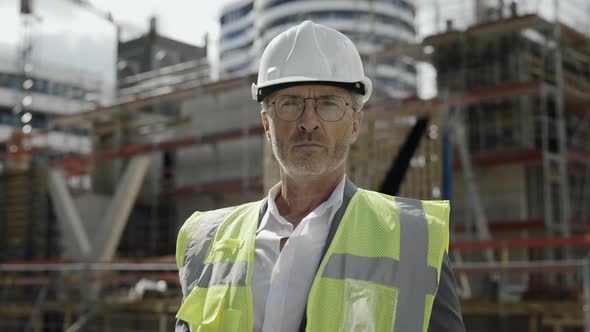 Portrait of Builder in Helmet Posing on Construction Site