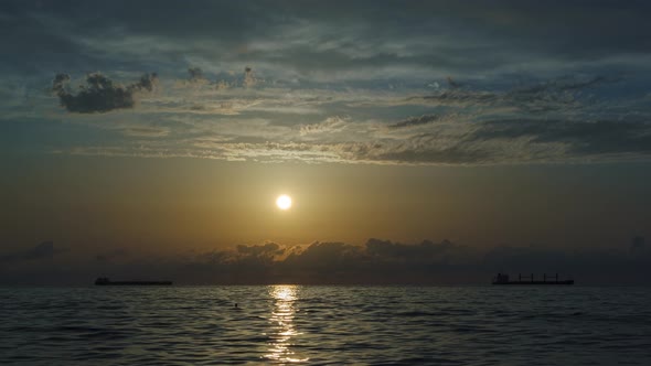 Against the background of the sea, the sun goes down, blue and orange clouds flow in sky. time lapse