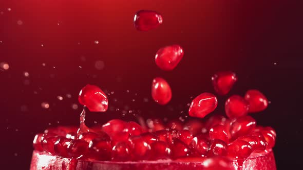 Pomegranate Grains Falling on Surface of Half Pomegranate in Slow Motion