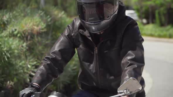 Slow Motion of Motorcyclist with Leather Jacket Sits on an Idle Motorcycle