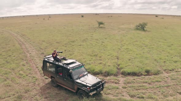 Photographer photographing from roof of vehicle while on african wildlife safari in Kenya. Aerial dr