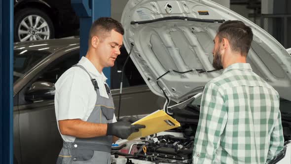 Car Mechanic Talking To the Client at Automotive Service Center