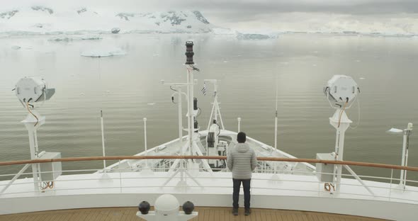 A person standin on the bow of the ship in winter time