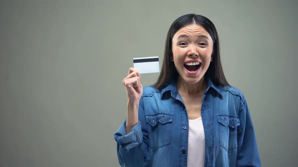 Asian Woman Holding Credit Card in Hands, Cash Back Services, Grey Background