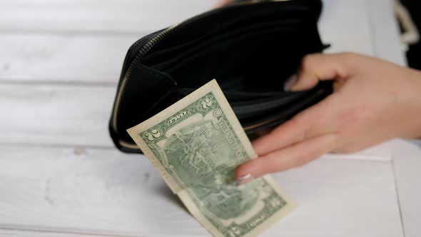 Hand of a Woman with an Empty Wallet and Two American Dollars Closeup