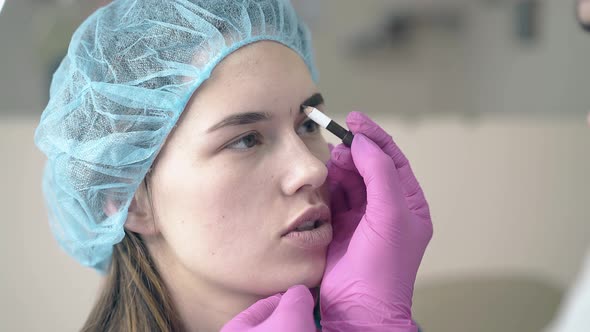 Cosmetologist Makes Tattooing on Client Eyebrows in Salon