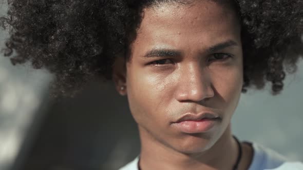 Close Up Portrait of Young African American Guy with Afro Hairstyle Looking Serious Smiling and