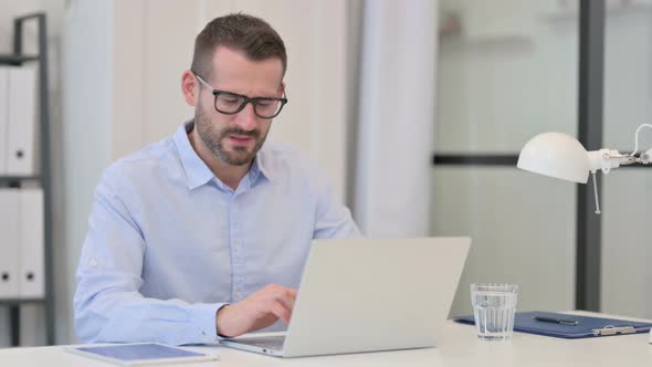 Middle Aged Man Having Headache While Working on Laptop