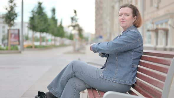 Old Woman Smiling at Camera While Sitting on Bench