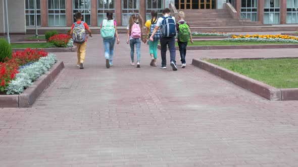 Junior Students with Schoolbags Walk To School Building