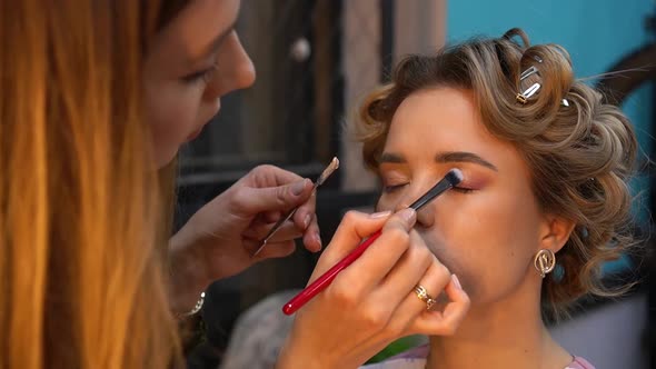 Professional Makeup Artist Applies Eye Shadow to Eyelid of Young Woman