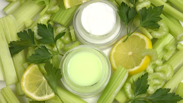 Jars of the natural lemon and celery-infused cream, fresh celery stalks and slices of the lemon