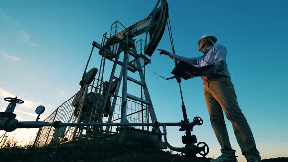 Male Engineer Is Observing a Working Oil Pumping Unit