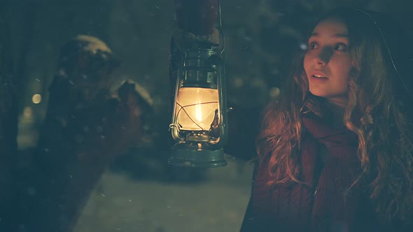 Young girl in winter forest with lantern