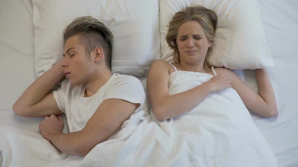Annoyed Woman Closing Ears While Man Snoring Loudly in Bed, Apnea Disease
