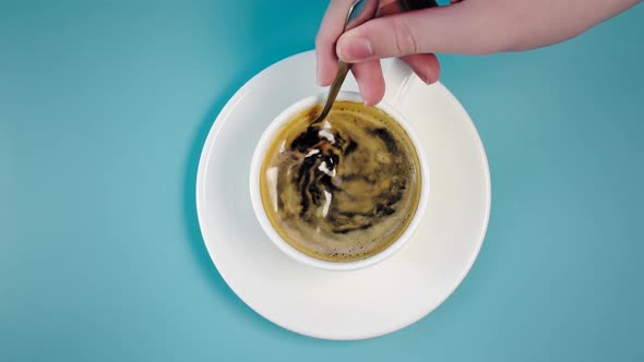 Person Stirs Coffee in White Cup