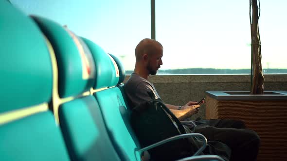 American Businessman Uses Smartphone While Sitting By Window at Airport Room Spbd