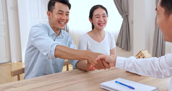 Male Real Estate Broker Shaking Hands With New Property Owners 