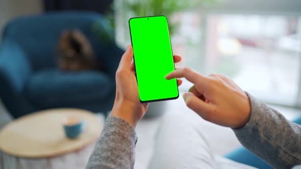 Woman at Home Using Smartphone with Green Mockup Screen in Vertical Mode