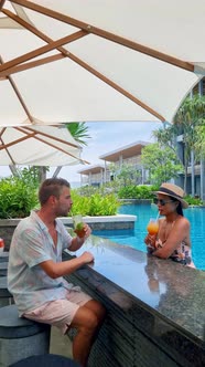 Couple Men and Women Drinking Cocktails By the Bar of a Tropical Pool During Vacation