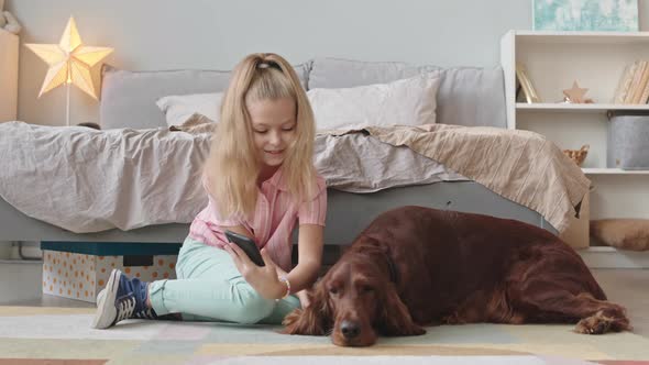 Girl with Smartphone Playing with Her Dog