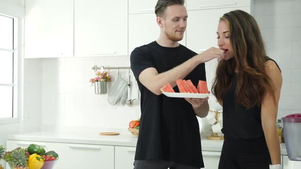 Man and woman eating fruit in kitchen