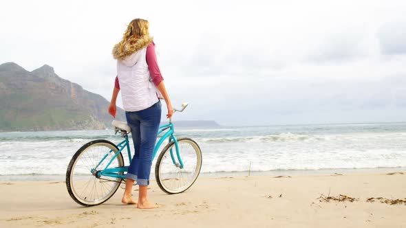 Woman standing with her bicycle on beach