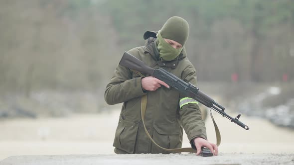 Confident Caucasian Masked Soldier Attaching Magazine To Rifled Gun and Walking Away in Slow Motion