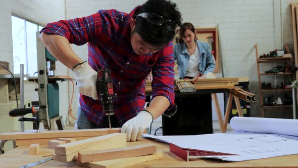 Craftsman drilling the wood on the workshop table by a hand drill in wood workshop