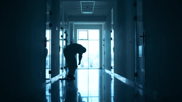 Doctor in a Protection Suit Sits on the Floor in the Corridor