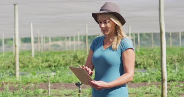 Video of caucasian woman with laptop standing in greenhouse