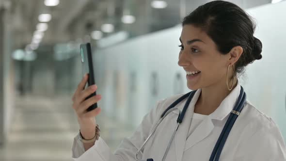 Cheerful Indian Female Doctor Talking on Smartphone in Cafe