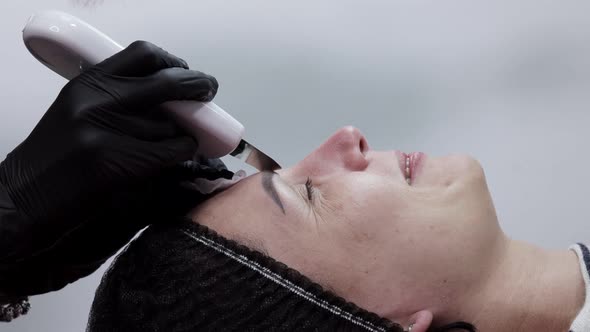 Cosmetologist, beautician making facial treatment with ultrasonic spatula