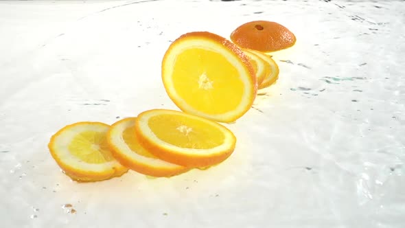 Orange Falls Into the Water and Flakes To the Lobules. White Background. Slow Motion